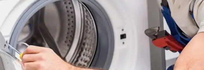 Appliance technician repairing a clothes dryer drum and internal parts in West Palm Beach, FL