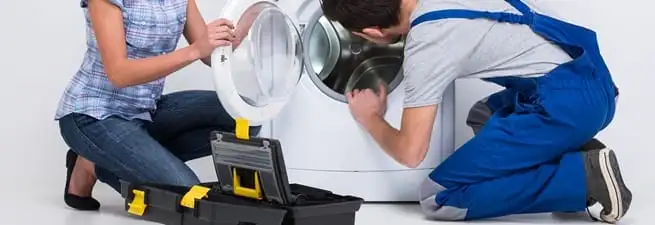 Washer repair technician inspecting a front-load washing machine with tools in West Palm Beach, FL