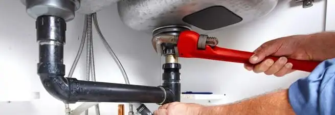 Garbage disposal repair technician tightening the sink drain and disposal connection in West Palm Beach, FL