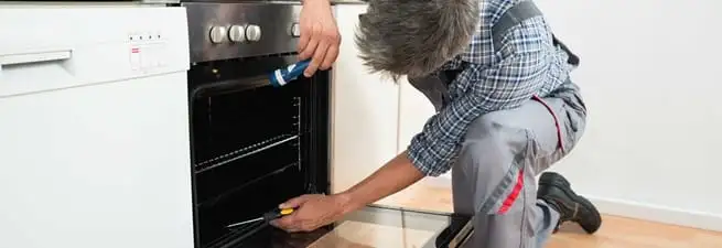 Oven repair technician inspecting and servicing an electric oven in West Palm Beach, FL