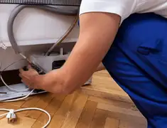 Appliance repair technician fixing refrigerator water line and connections in West Palm Beach, FL