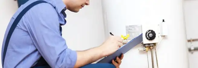 Water heater repair technician inspecting the unit and recording service notes in West Palm Beach, FL