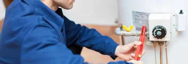 Water heater repair technician adjusting the temperature control and gas valve in West Palm Beach, FL